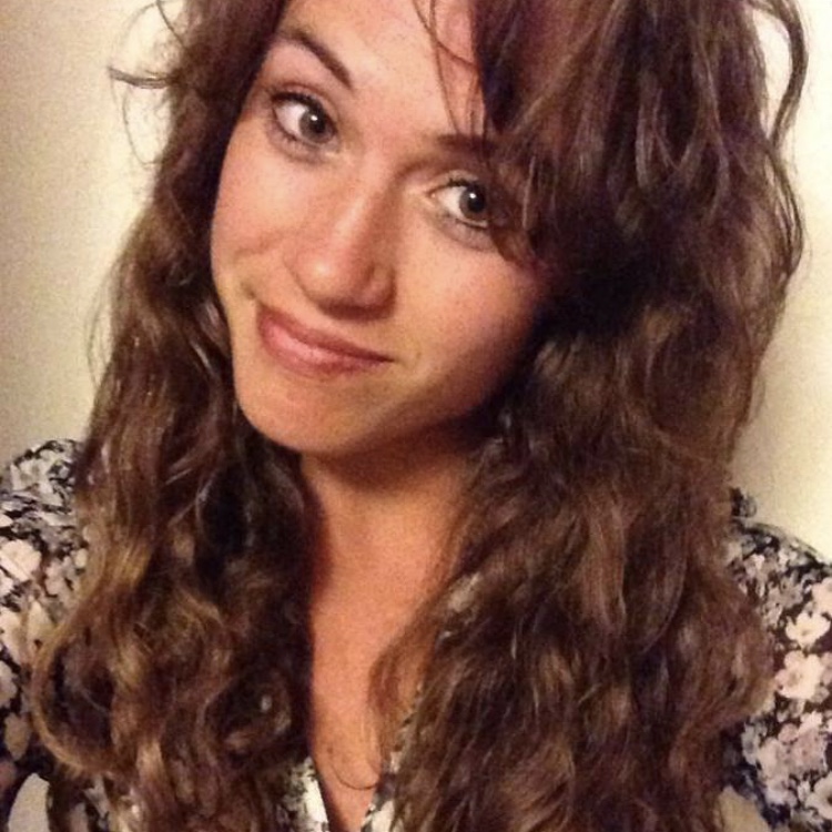 This image shows Danielle, a woman with long and curly brown hair, and a smirk on her face.