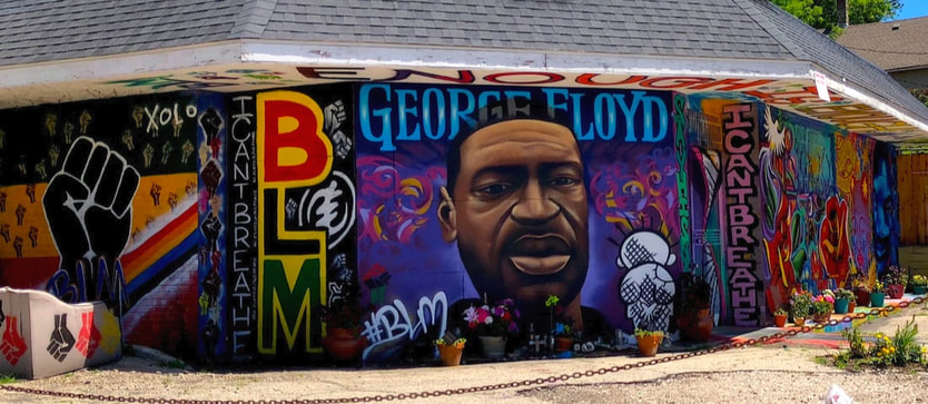 A mural featuring a likeness of George Floyd and Black Lives Matter fist, painted on a building on the corner of North and Holton in Milwaukee, WI.