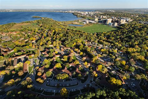 aerial photo of the graduate housing neighborhood in Madison, WI. Brown buildings are scattered among trees next to a large lake.