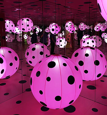 Jason inside Yayoi Kusama exhibit featuring pink polka dotted balloons and infinity mirrors