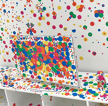 Kusama installation featuring white replica computer monitor covered in dot stickers of multiple colors