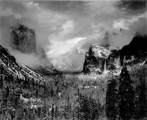 B/W photograph of Yosemite Valley wrapped in thick clouds. 