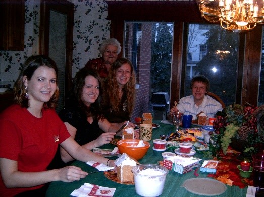 Image of 5 family members around kitchen table making gingerbread houses.